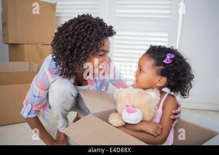 Niedliche Tochter sitzen in beweglichen Box Holding Teddy mit Mutter Stockfoto