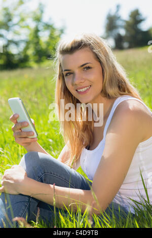 Hübsche Blondine sitzen auf dem Rasen eine SMS Stockfoto