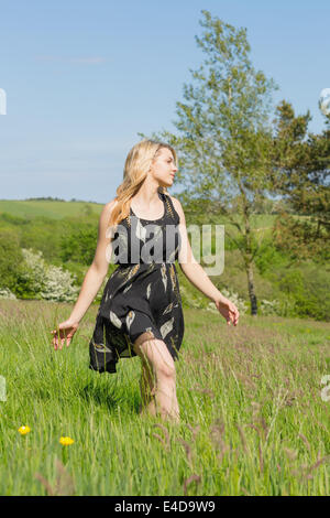 Hübsche Blondine im Sommerkleid ein Spaziergang durch Feld Stockfoto