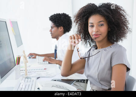 Junge Editor lächelnd in die Kamera an ihrem Schreibtisch Stockfoto