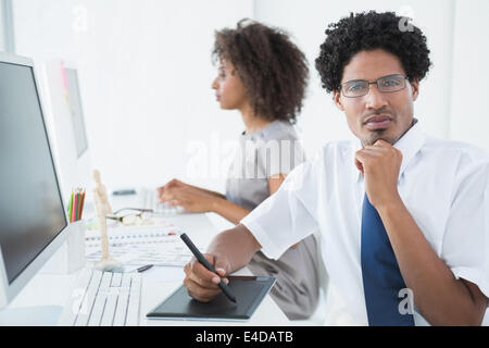 Junge Designer, Blick in die Kamera an seinem Schreibtisch Stockfoto