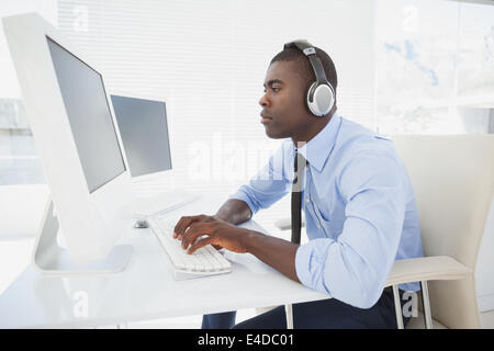 Konzentrierte sich Geschäftsmann arbeitet an seinem Schreibtisch Musik hören Stockfoto