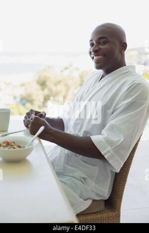 Gut aussehender Mann im Bademantel frühstücken außerhalb Stockfoto
