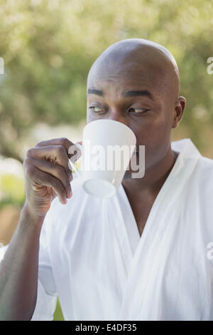 Gut aussehender Mann im Bademantel Kaffeetrinken außerhalb Stockfoto