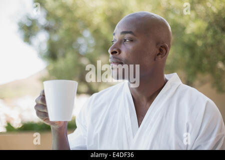 Gut aussehender Mann im Bademantel Kaffeetrinken außerhalb Stockfoto