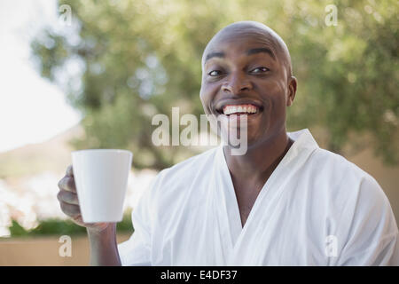 Gut aussehender Mann im Bademantel Kaffeetrinken außerhalb Stockfoto