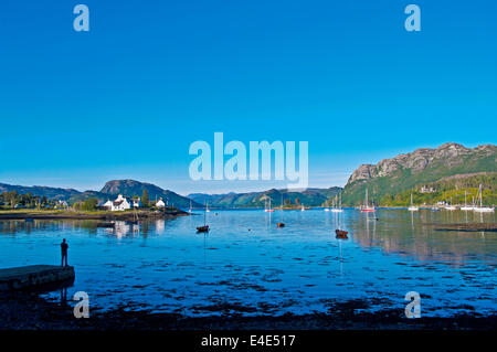 Mann auf der Mole mit Blick auf Boote vertäut im Hafen von Plockton, ruhigen Sommerabend, Loch Carron, Wester Ross, Schottland, Vereinigtes Königreich Stockfoto