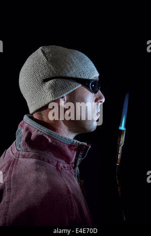 Mann hält einen beleuchteten Lötlampe. Stockfoto