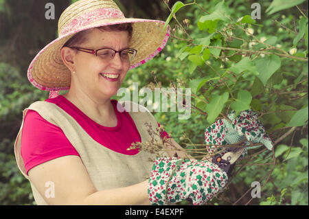 Reife Frau im Garten, Kreuz bearbeitete Bild beschneiden Schere verwenden Stockfoto