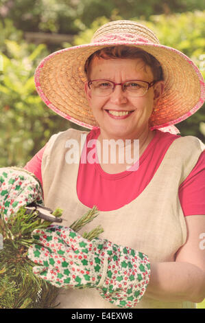 Reife Frau im Garten, Kreuz bearbeitete Bild beschneiden Schere verwenden Stockfoto