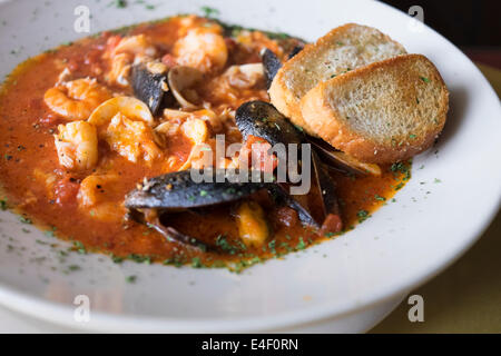 Meeresfrüchte Suppenteller mit Muscheln, Muscheln, Fisch, Garnelen, Tomate würfeln und geröstetes Knoblauchbrot wie in Italien serviert. Stockfoto