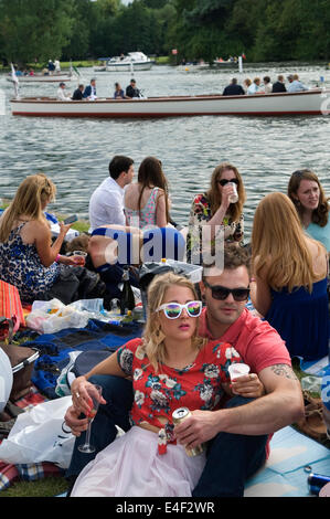 Henley auf der Thames Royal Regatta UK. Menschenmassen beobachten die Rennen vom Flussufer aus. Paar Frau trägt weiße modische gerahmte Gläser und nicht beobachten die Rennen, nur hängen und gesehen, um dort zu sein. 2014 HOMER SYKES in den 2010er Jahren Stockfoto