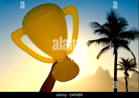 Hand mit aufblasbaren Trophäe über Sonnenuntergang Skyline von Rio De Janeiro Brasilien Stockfoto