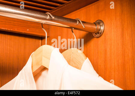 Weißen Bademantel an Holz Kleiderbügel im Schrank hängen Stockfoto