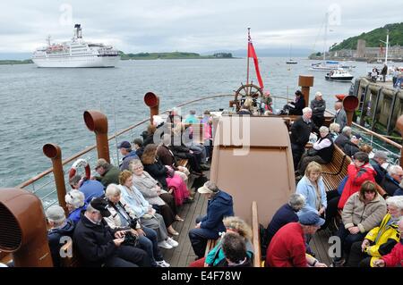 Die Waverley Raddampfer fährt Oban Pier, als ein Kreuzfahrtschiff in der Bucht verankert liegt Stockfoto