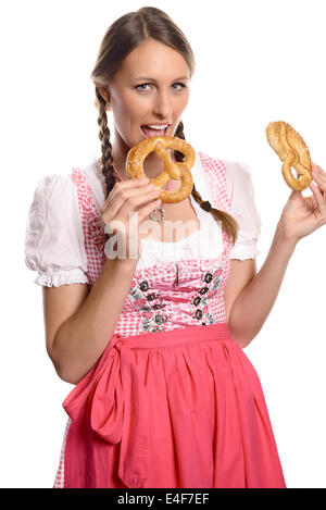 Glücklich attraktive deutsche oder bayerische Frau in einem traditionellen Dirndl, den Mund zu öffnen, eine frische Brezel zu essen Stockfoto