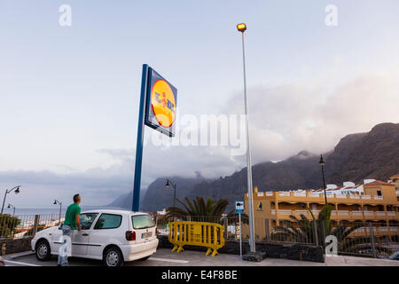 Parkhaus und Lidl-Supermarkt unterzeichnen in Puerto Santiago mit Blick auf die Klippen von Los Gigantes, Teneriffa, Kanarische Inseln, Spanien. Stockfoto