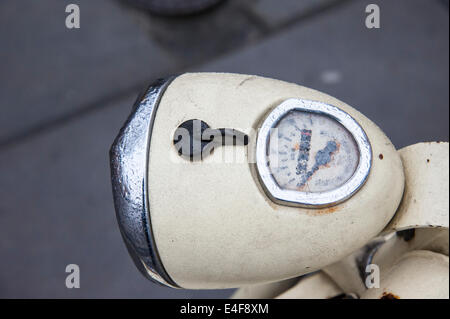 Ein regen bedeckt Scheinwerfer und Tacho von einem alten Moped angekettet an einen Pfosten auf einer Straße in Krakau. Stockfoto