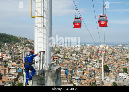 RIO DE JANEIRO, Brasilien - 22. Oktober 2013: Instandhalter klettert einen Beitrag unterstützen Seilbahnen über Favela Complexo Alemao Stockfoto
