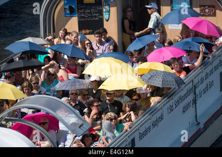 Berlin, Deutschland. 10. Juli 2014. Passagier der Fähre Boot schützen sich vor der Sonne mit Sonnenschirmen in Berlin, Deutschland, 10. Juli 2014. Foto: MAURIZIO GAMBARINI/Dpa/Alamy Live News Stockfoto