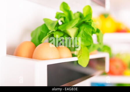 Offenen Kühlschrank, Eiern mit frischen grünen Rocca auf dem Regal der Kühlschranktür, Bio-Lebensmittel, gesunde Ernährungskonzept Stockfoto