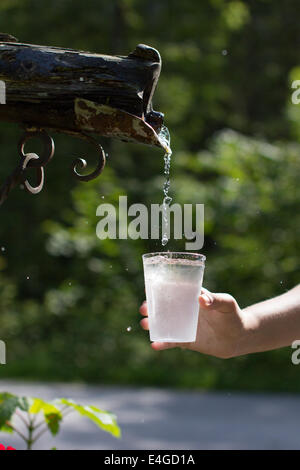 Wasser tropft aus den alten Wasserhahn zum cup Stockfoto