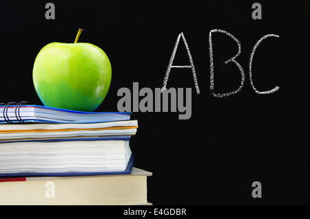 ABC geschrieben auf einer Tafel mit Büchern und Apfel vor Stockfoto