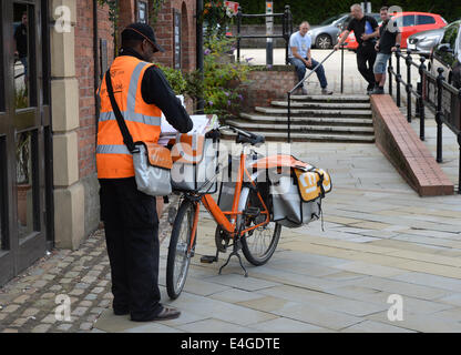Ein TNT Postbote liefert Post an eine Adresse in Manchester City Centre, Stockfoto