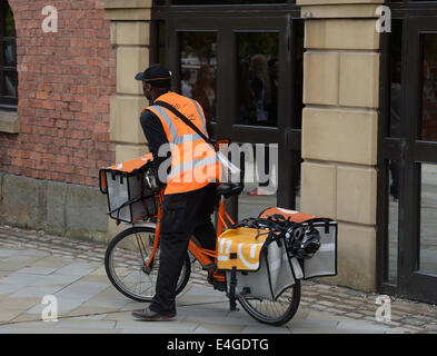 Ein TNT Postbote liefert Post an eine Adresse in Manchester City Centre, Stockfoto