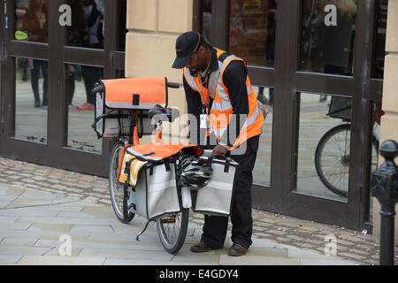 Ein TNT Postbote liefert Post an eine Adresse in Manchester City Centre, Stockfoto