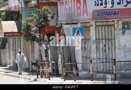 Gaza-Stadt, Gazastreifen, Palästinensische Gebiete. 11. Juli 2014. Ein palästinensischer Mann Spaziergänge entlang einer Haupteinkaufsstraße mit Fensterläden Läden in der Innenstadt von Gaza-Stadt, am 11. Juli 2014. Aufgrund der Situation sind die Straßen von Gaza während des ganzen Tages, Menschen sind Angst, da in der Regel gehen und lieber zu Hause bleiben leer. Israel drückte auf einen vierten Tag mit der Gaza-Offensive am Freitag, die Hamas dominierten Enklave von Luft- und Seefracht, auffällig, wie palästinensische militante aufrechtgeerhalten Angriffe tief Rakete in den jüdischen Staat. Bildnachweis: ZUMA Press, Inc./Alamy Live-Nachrichten Stockfoto