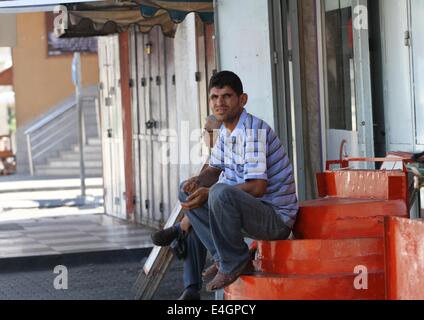Gaza-Stadt, Gazastreifen, Palästinensische Gebiete. 11. Juli 2014. Ein palästinensischer Mann sitzen auf einer Haupteinkaufsstraße mit Fensterläden Läden in der Innenstadt von Gaza-Stadt, am 11. Juli 2014. Aufgrund der Situation sind die Straßen von Gaza während des ganzen Tages, Menschen sind Angst, da in der Regel gehen und lieber zu Hause bleiben leer. Israel drückte auf einen vierten Tag mit der Gaza-Offensive am Freitag, die Hamas dominierten Enklave von Luft- und Seefracht, auffällig, wie palästinensische militante aufrechtgeerhalten Angriffe tief Rakete in den jüdischen Staat. Bildnachweis: ZUMA Press, Inc./Alamy Live-Nachrichten Stockfoto