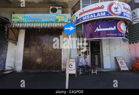 Gaza-Stadt, Gazastreifen, Palästinensische Gebiete. 11. Juli 2014. Ein palästinensischer Mann sitzen auf einer Haupteinkaufsstraße mit Fensterläden Läden in der Innenstadt von Gaza-Stadt, am 11. Juli 2014. Aufgrund der Situation sind die Straßen von Gaza während des ganzen Tages, Menschen sind Angst, da in der Regel gehen und lieber zu Hause bleiben leer. Israel drückte auf einen vierten Tag mit der Gaza-Offensive am Freitag, die Hamas dominierten Enklave von Luft- und Seefracht, auffällig, wie palästinensische militante aufrechtgeerhalten Angriffe tief Rakete in den jüdischen Staat. Bildnachweis: ZUMA Press, Inc./Alamy Live-Nachrichten Stockfoto