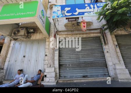 Gaza-Stadt, Gazastreifen, Palästinensische Gebiete. 11. Juli 2014. Palästinenser sitzt auf einer Haupteinkaufsstraße mit Fensterläden Läden in der Innenstadt von Gaza-Stadt, am 11. Juli 2014. Aufgrund der Situation sind die Straßen von Gaza während des ganzen Tages, Menschen sind Angst, da in der Regel gehen und lieber zu Hause bleiben leer. Israel drückte auf einen vierten Tag mit der Gaza-Offensive am Freitag, die Hamas dominierten Enklave von Luft- und Seefracht, auffällig, wie palästinensische militante aufrechtgeerhalten Angriffe tief Rakete in den jüdischen Staat. Bildnachweis: ZUMA Press, Inc./Alamy Live-Nachrichten Stockfoto