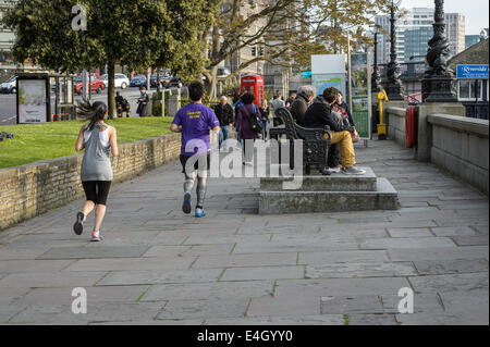 Eine junge Frau weiblich und Mann männlich läuft entlang der Themse an einem Frühlingsabend nach der Arbeit, London UK Stockfoto