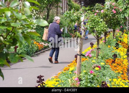 Besucher gehen durch Blumenrabatten in Bad Gärten, eine öffentliche Grünfläche in Bakewell Stadtmitte, Peak District, Derbyshire, UK Stockfoto