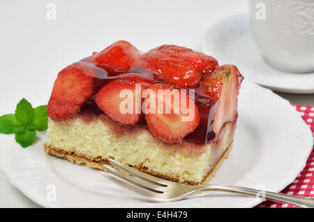 ein Stück Erdbeertorte auf weißem Teller weiß Kaffeetasse und Gabel, Nahaufnahme Stockfoto