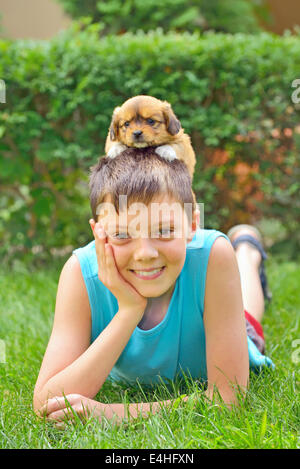 Junge spielt mit einem Welpen im Garten Stockfoto