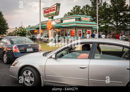 Lange Schlangen von Kunden, beide stehen und in Autos, warten geduldig für den süßen Geschmack des Südens, Krispy Kreme Doughnuts. Stockfoto
