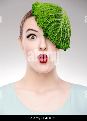 Porträt einer Frau, die zur Veranschaulichung einer Vegan-Konzepts mit einem Kohl auf dem Kopf Stockfoto