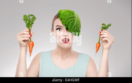 Porträt einer Frau zur Veranschaulichung ein Vegan-Konzept hält eine Karotten und Kohl auf dem Kopf mit Stockfoto