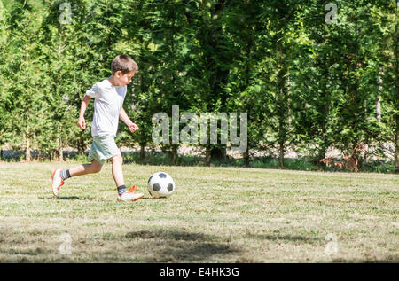 Kinder spielen Fußball in einem Stadion. Bäume auf dem Grund Stockfoto