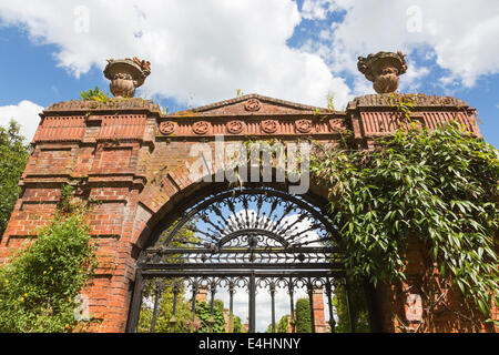 Mauerwerk Bogen und schwarzem Schmiedeeisen Schmiedeeisen Tor zum Walled Garden von Sandringham House, Norfolk, Großbritannien mit blauem Himmel und weißen Wolken Stockfoto