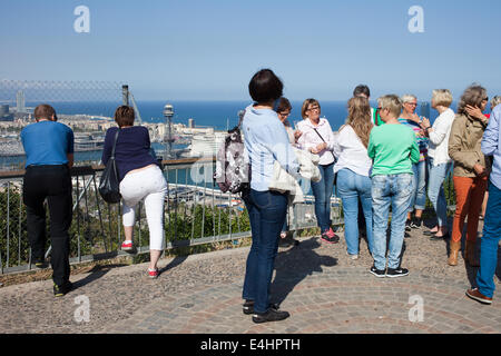 Gruppe von Touristen, vor allem Frauen auf einer geführten Tour am Montjuic Aussichtspunkt mit Blick auf Barcelona und das Meer in Katalonien, Spanien. Stockfoto