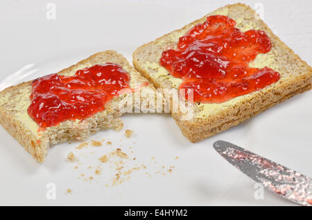 zwei Scheiben Toast mit Erdbeermarmelade und Butter auf weißen Teller, Nahaufnahme, full frame Stockfoto