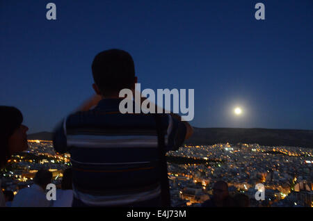 Athen, Griechenland. 12. Juli 2014. Menschen fotografieren Vollmond, da es über Athen erhebt. Ein Supermoon tritt auf, wenn der Mond etwas näher an der Erde ist, als es in der Regel ist, und der Effekt am deutlichsten, ist wenn sie zur gleichen Zeit wie ein Vollmond auftritt. Bildnachweis: George Panagakis/Pacific Press/Alamy Live-Nachrichten Stockfoto