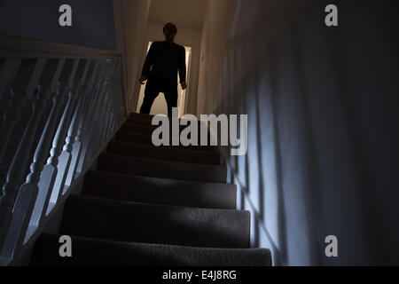 Silhouette eines Mannes stehen an der Spitze einer Treppe, Schatten an den Wänden des Lichts unter. Stockfoto