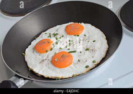 Spiegeleier mit drei Eigelb und Schnittlauch in einer Pfanne erhitzen, Nahaufnahme Stockfoto