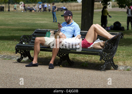 Kensington, London, UK. 13. Juli 2014. Menschen entspannen auf Parkbänken an einem warmen Tag im Hyde Park in London an einem warmen Tag des sonnigen Wetters Credit: Amer Ghazzal/Alamy Live-Nachrichten Stockfoto