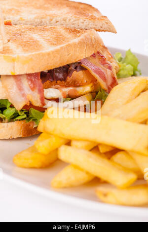 Köstliche dünn geschnittenes Rindfleisch Pastrami-Club-Sandwich mit frischem lockige Salat mit eine kleine Schüssel mit eingelegtem Gemüse serviert auf einem Stockfoto